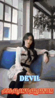 a woman is sitting on a couch in front of a window with the words " devil " written on it