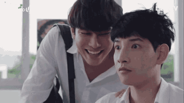 a couple of young men are standing next to each other and laughing .