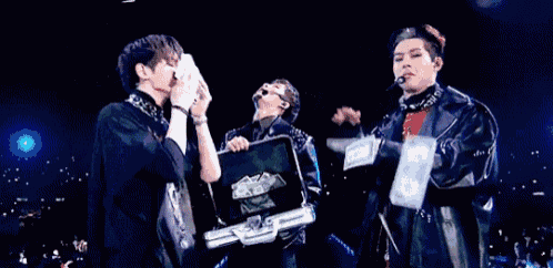a group of men are standing next to each other on a stage holding a briefcase full of money .