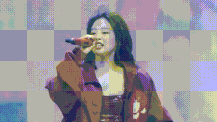 a woman is singing into a microphone on a stage .