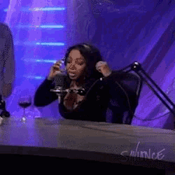 a woman is sitting at a table with a microphone and a sign that says winlee