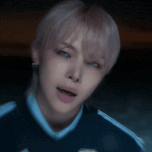 a close up of a person 's face with a blue shirt on and a ponytail .