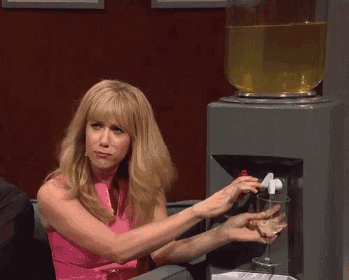 a woman in a pink dress is pouring a glass of wine into a water dispenser