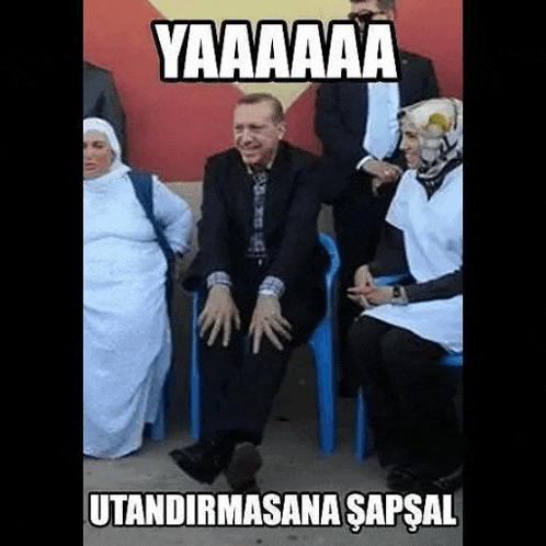 a man in a suit is sitting in a blue chair next to a group of women .