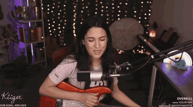 a woman playing a guitar in front of a microphone with the word kiger on the bottom right