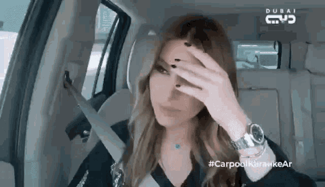 a woman covering her face in a car with dubai written on the back