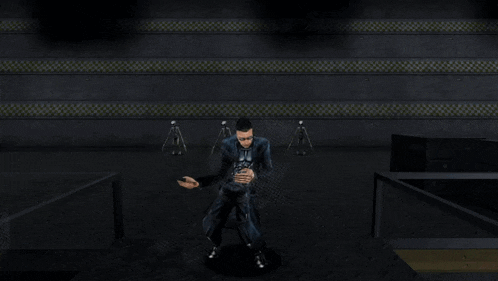 a man in a black suit is standing in a dark room with his hands up