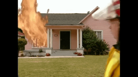 a fireman stands in front of a pink house with flames coming out of the roof