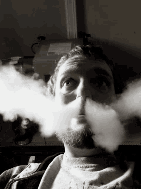 a man with a beard is blowing smoke from his mouth