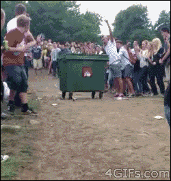 a crowd of people are gathered around a green dumpster that says recycling