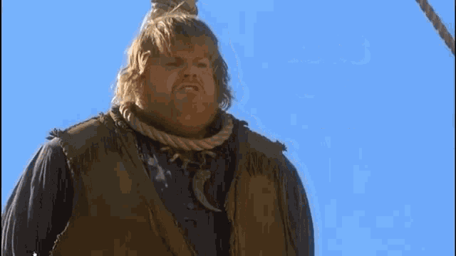 a fat man with a rope around his neck is standing next to a blue sky .