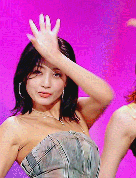 a woman in a strapless dress is waving her hand in front of a pink background
