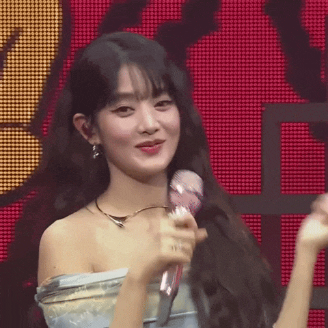 a woman is holding a microphone in front of a red screen .
