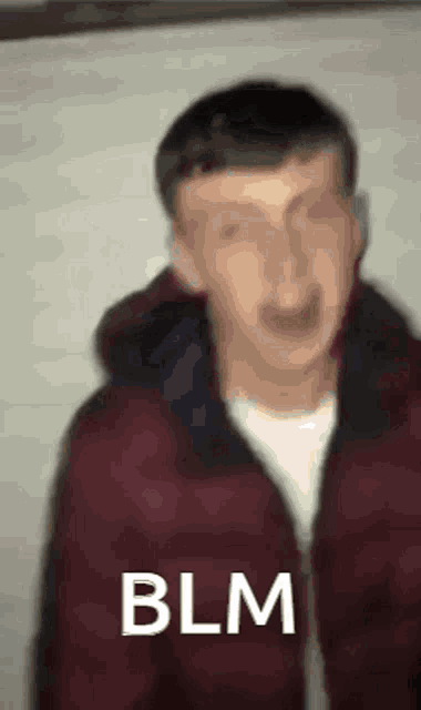 a blurry picture of a man wearing a red jacket with the words blm written on it .