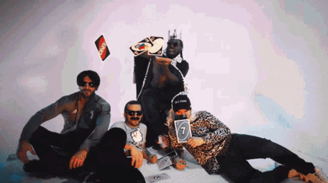 a group of men are posing for a picture and one of them is holding a 7 card