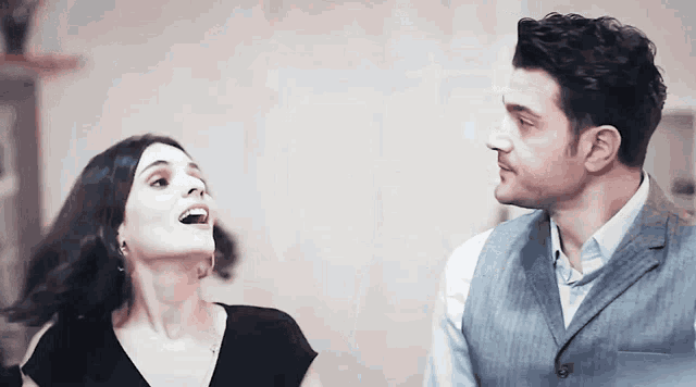 a man and a woman are looking at each other and the woman is laughing