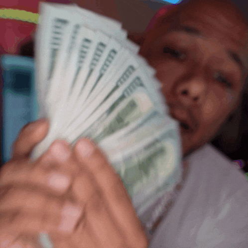 a man is holding a fan of money in his hands