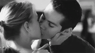 a black and white photo of a man and woman kissing each other .