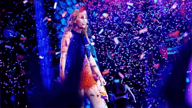 a woman is standing on a stage surrounded by confetti and a microphone .