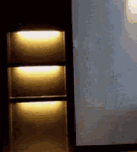 three shelves are lit up in a dark room with a white wall behind them