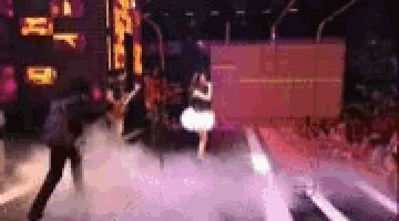 a group of people are dancing on a stage in front of a large screen .