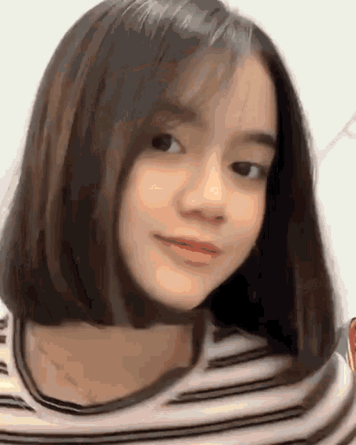 a young girl with short hair is wearing a striped shirt and smiling .