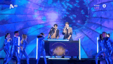 a group of people are dancing on a stage with a hd logo in the upper right corner