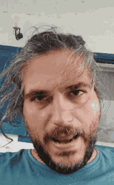 a man with long gray hair and a beard is wearing a blue shirt