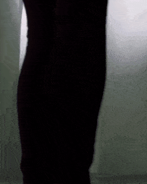 a silhouette of a person standing in front of a white curtain in a dark room .