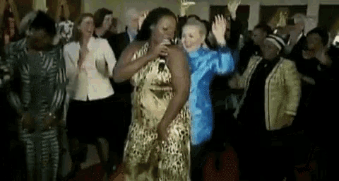 a woman in a leopard print dress is singing into a microphone while dancing in front of a crowd .