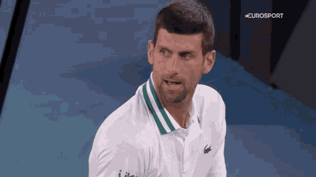 a man wearing a white shirt with a green and white collar and eurosport written on the bottom