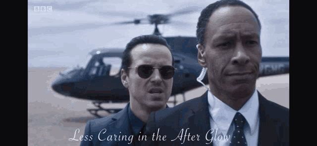 two men are standing in front of a helicopter with the words less caring in the after glow