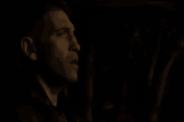 a close up of a man 's face in the dark with his mouth open .