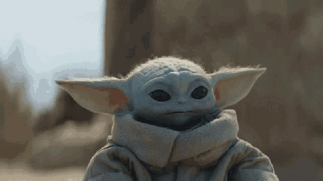 a close up of a baby yoda looking at the camera with a serious look on his face .