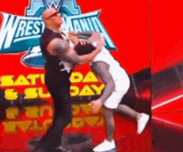 two men wrestling in front of a sign that says wrestlemania