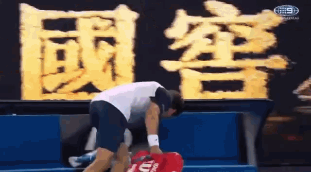 a man in a white shirt and blue shorts is holding a red bag that says ' ua ' on it