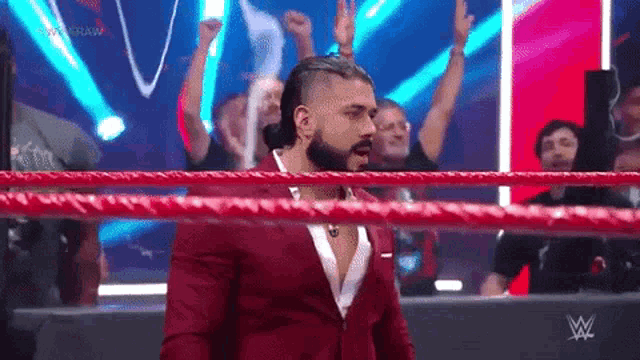 a man in a suit is standing in a wrestling ring .
