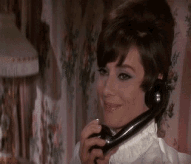 a woman is smiling while talking on a telephone in a room .