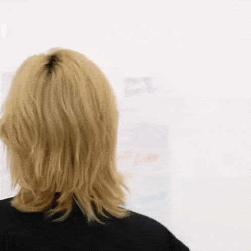 a woman with blonde hair is looking at a white board .