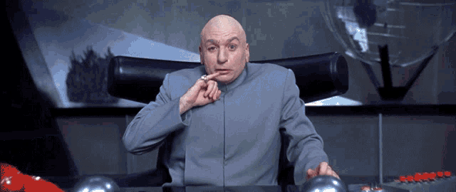 a bald man is sitting at a desk with his hand on his chin