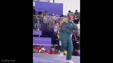a man is playing tennis in front of a crowd while holding a tennis racket .