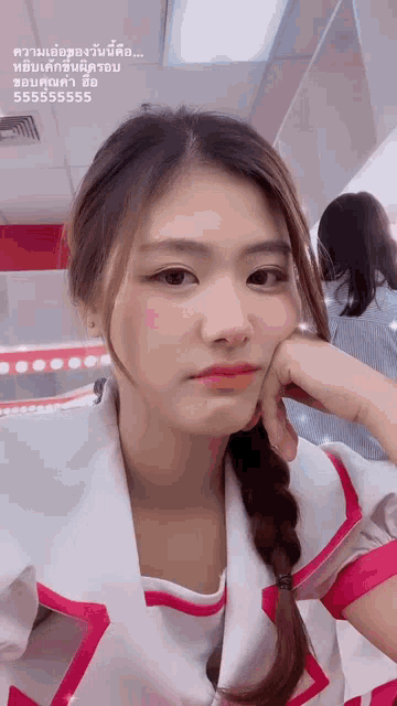 a girl with a braided ponytail is taking a selfie with her hand on her face .