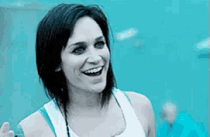 a woman in a white tank top is smiling in front of a pool .