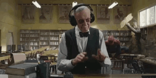 an elderly man wearing headphones is sitting at a table in a library .