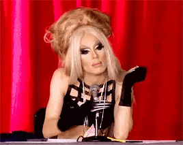 a drag queen is sitting at a desk in front of a microphone .