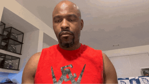 a bald man with a beard wears a red tank top with a nike logo