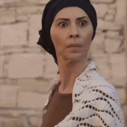 a woman wearing a black head scarf and a white sweater
