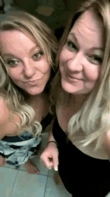 two women are standing next to each other and smiling for a picture .