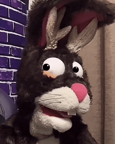 a close up of a stuffed rabbit with a purple brick wall in the background