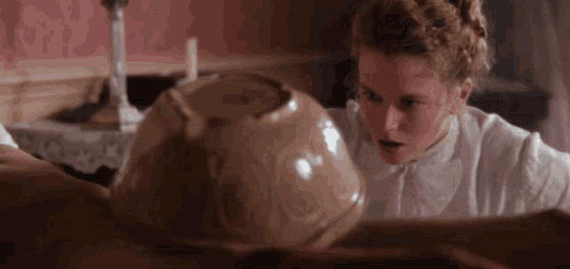 a woman in a white shirt looks at a large bowl